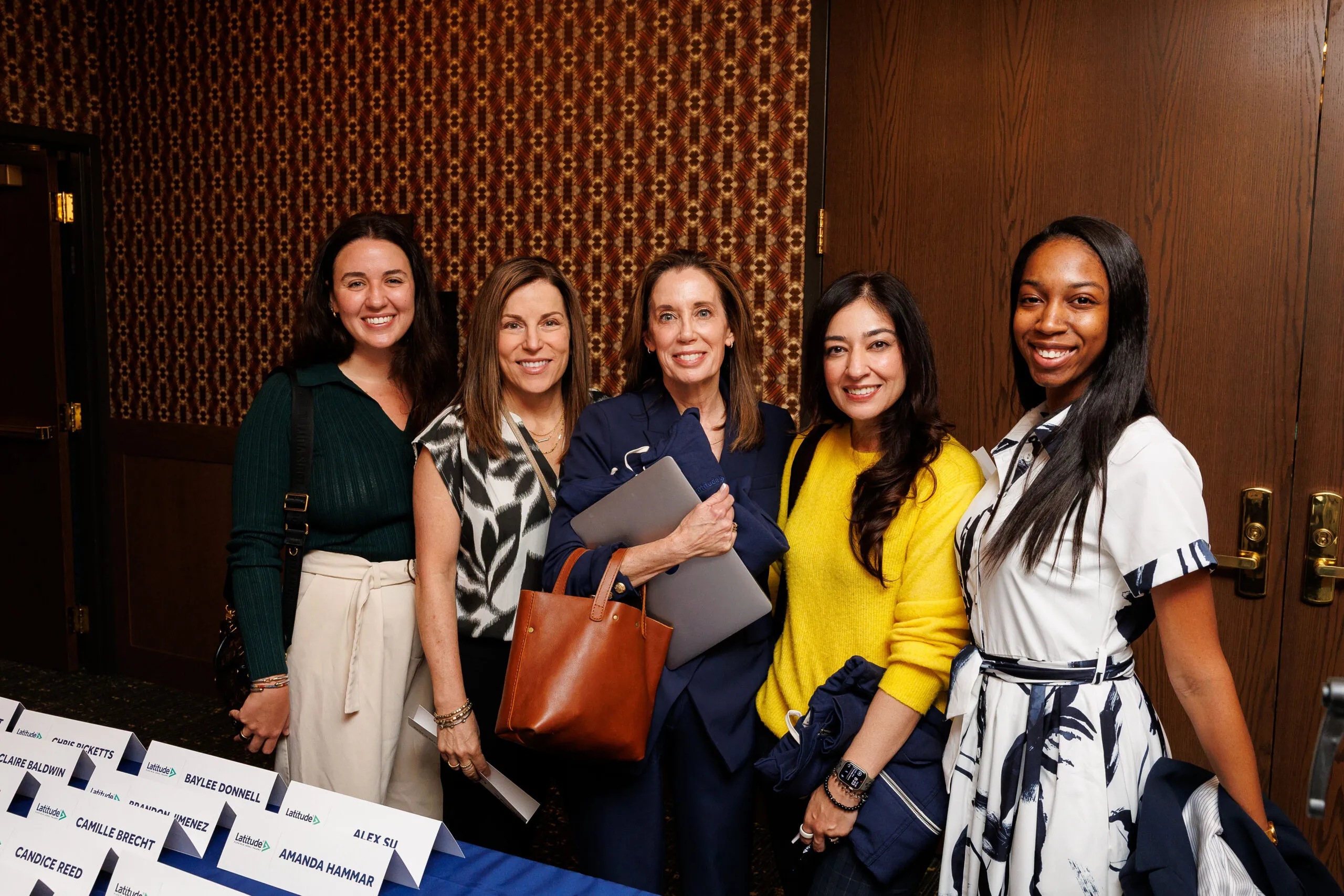 Group of women in front of nametag table, smiling for a photo