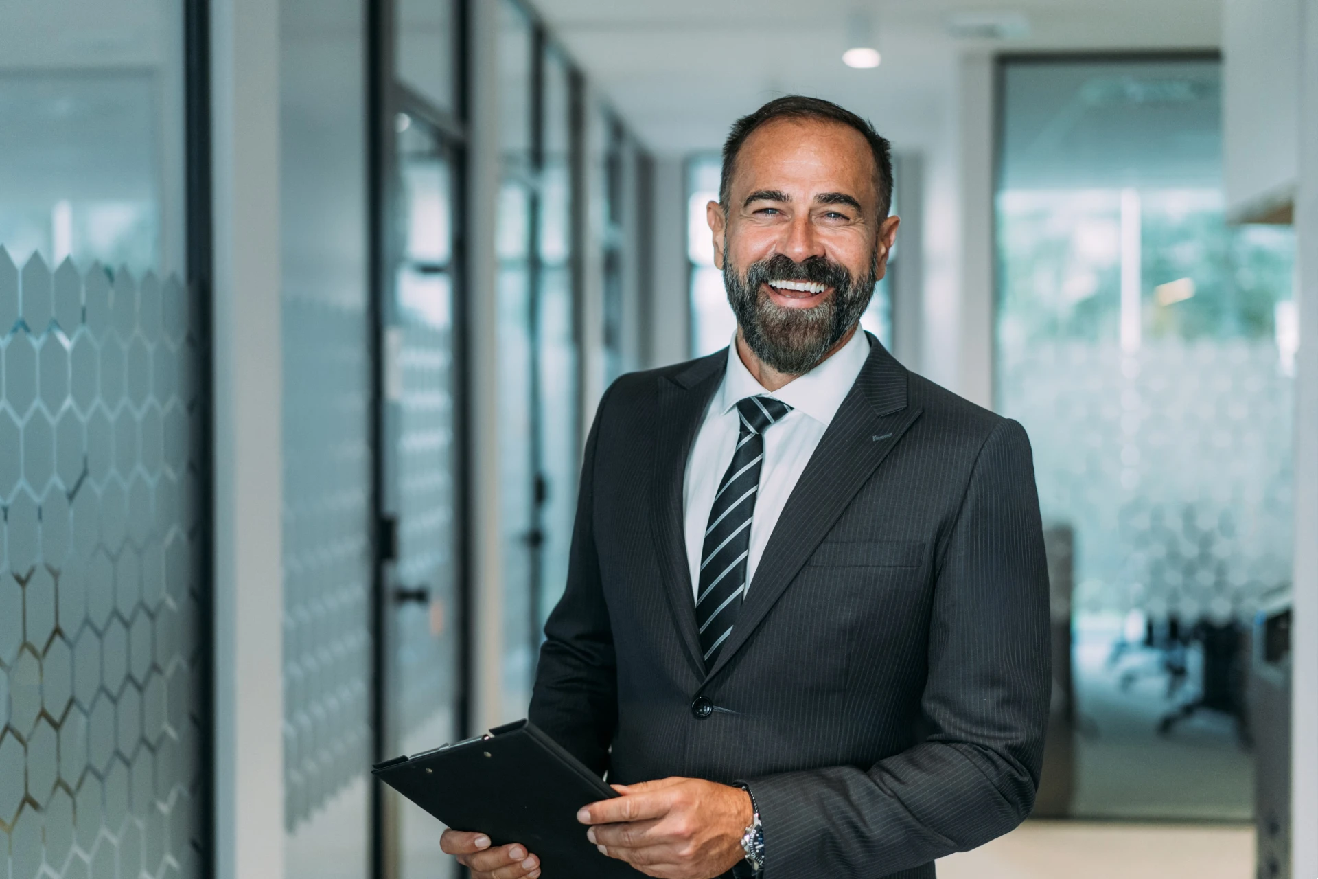 Shot of smiling businessman standing in his office and holding clipboard.