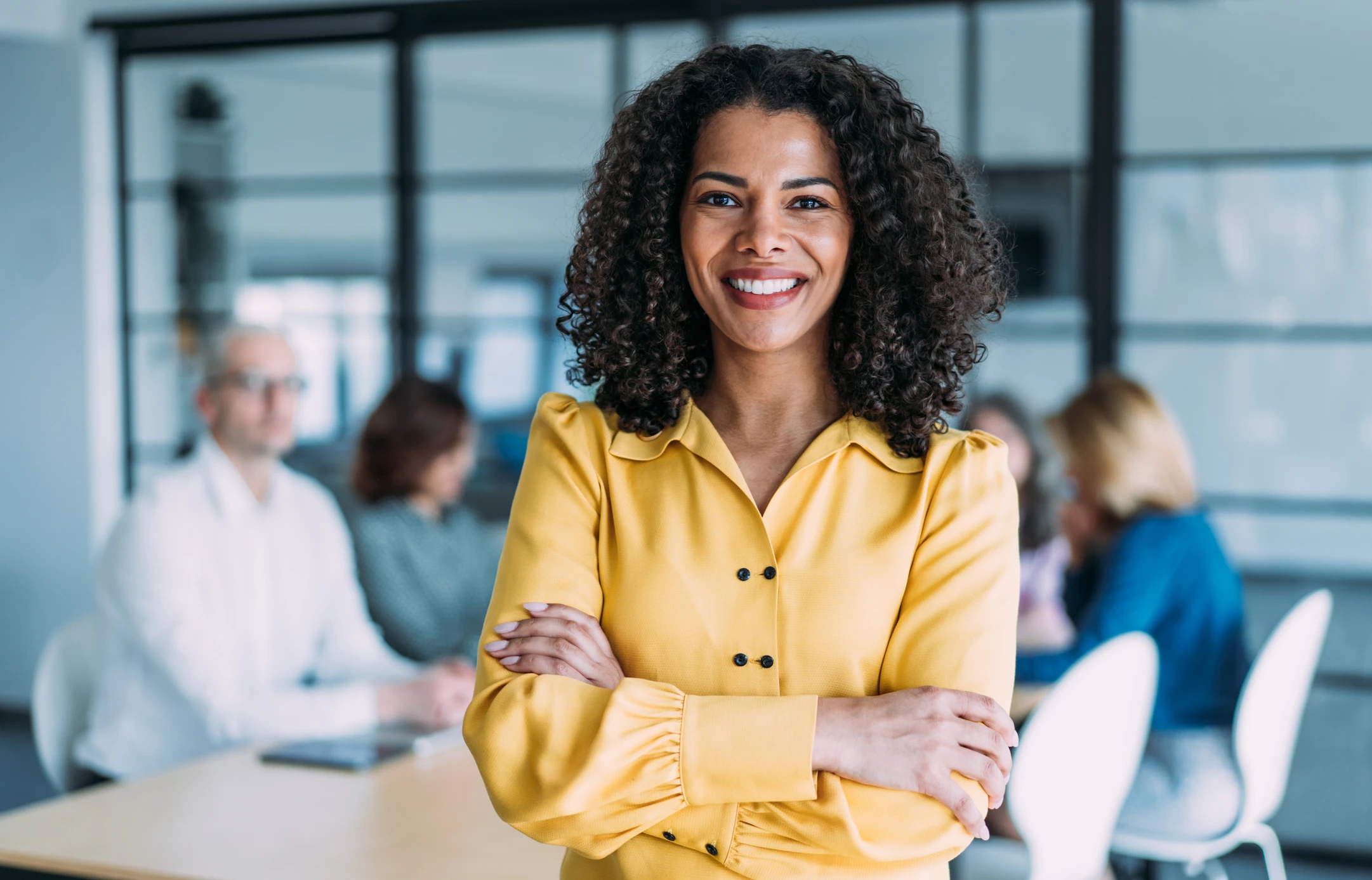 Shot of a smiling businesswoman standing in front of her team in modern office.